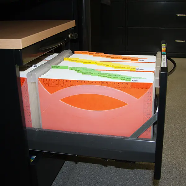 Ordnung mit Mappei Blick in einen geöffneten Schubladenschrank, gefüllt mit transparenten MAPPEI Ordnungsboxen und farbigen Reitern, die eine effiziente und übersichtliche Dokumentenorganisation ermöglichen.