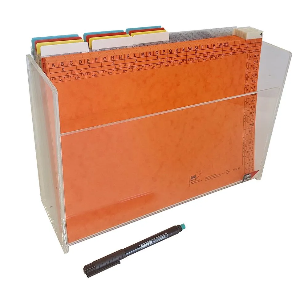 Acrylbox zur Hälfte gefüllt mit Aktionsmappen mit angebrachten Beschriftungsläufern, davor befinden sich mehrere orangene Leitkarten. Vor der Box liegt ein Stift