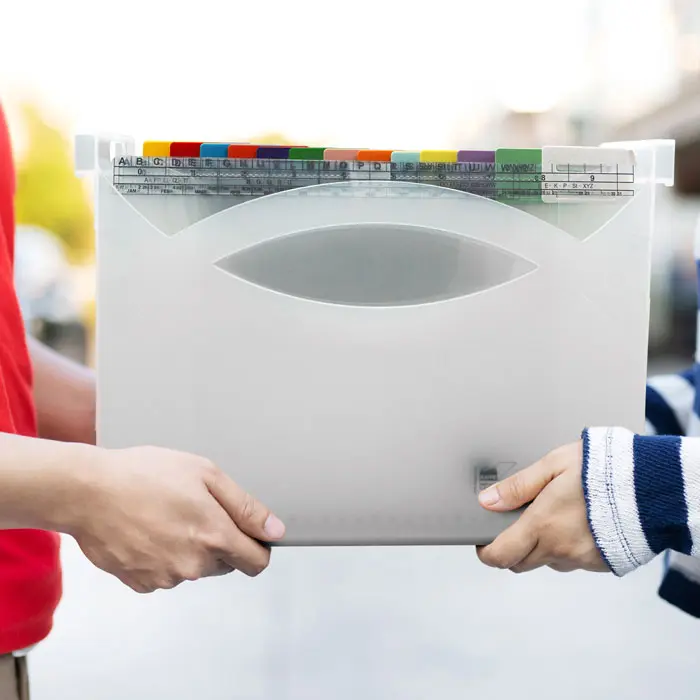 2 Personen stehen sich gegenüber und halten gemeinsam eine Mappei Ordnungsbox.