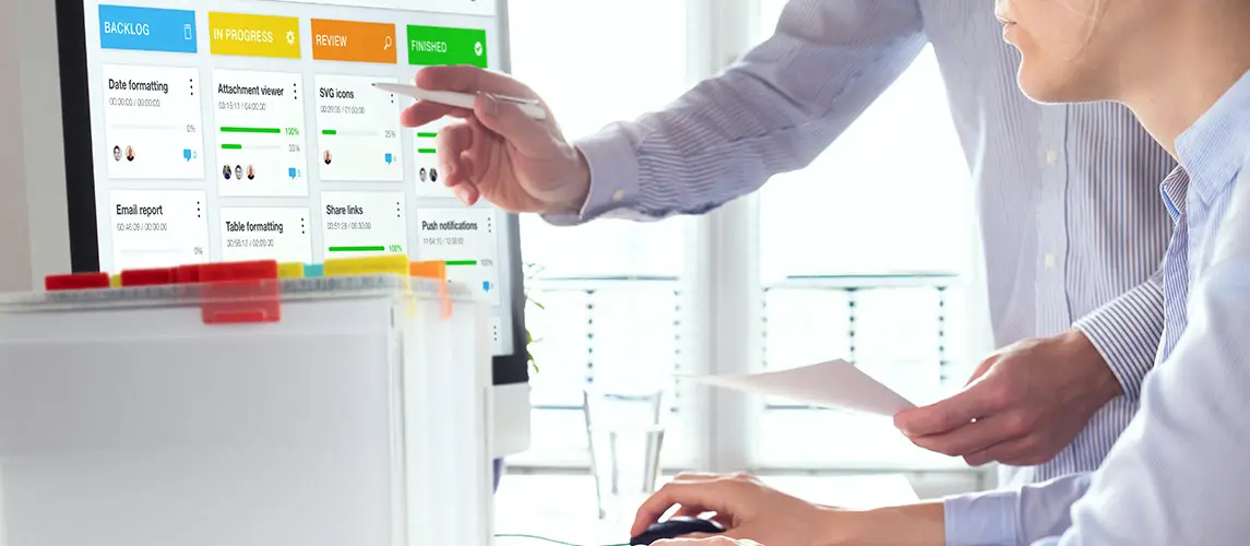 Nutzen und Vorteile Zwei Personen arbeiten gemeinsam an einem digitalen Projektmanagement-Board auf einem Computerbildschirm, um Aufgaben zu planen, zu verfolgen und den Fortschritt im Büro zu optimieren. Im Vordergrund eine Ordnungsbox von MAPPEI